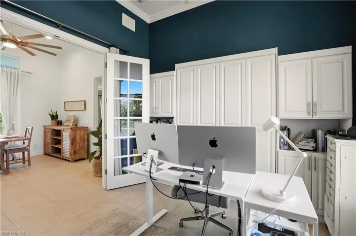 Office with a ceiling fan, a high ceiling, light tile patterned floors, and ornamental molding