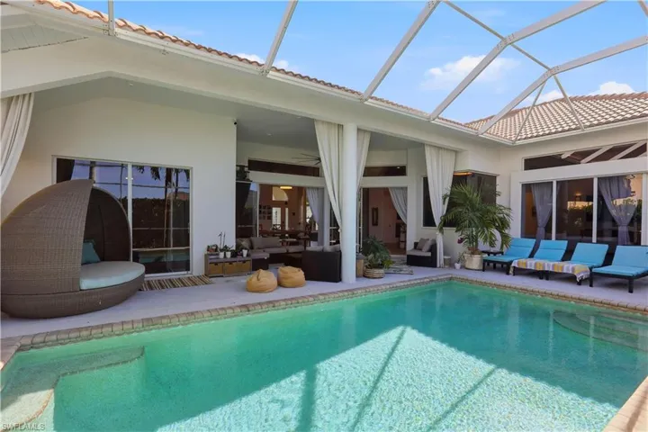 Swimming pool featuring an outdoor hangout area, a sunroom, a patio, and glass enclosure