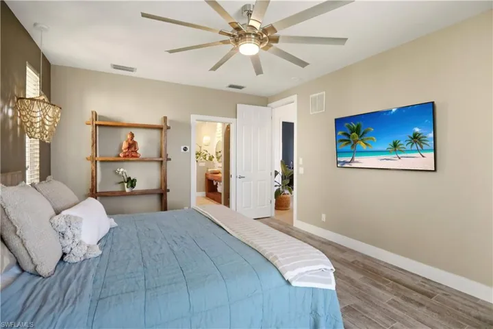 Bedroom with wood finish floors, ceiling fan, and ensuite bathroom