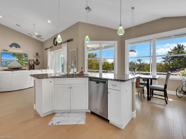 Kitchen featuring pendant lighting, dark stone counters, sink, stainless steel dishwasher, and white cabinetry