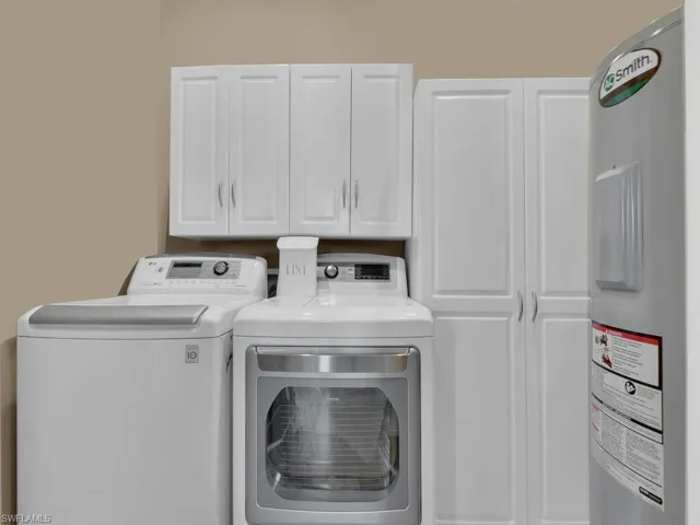 Washroom with cabinets, washing machine and dryer, and water heater