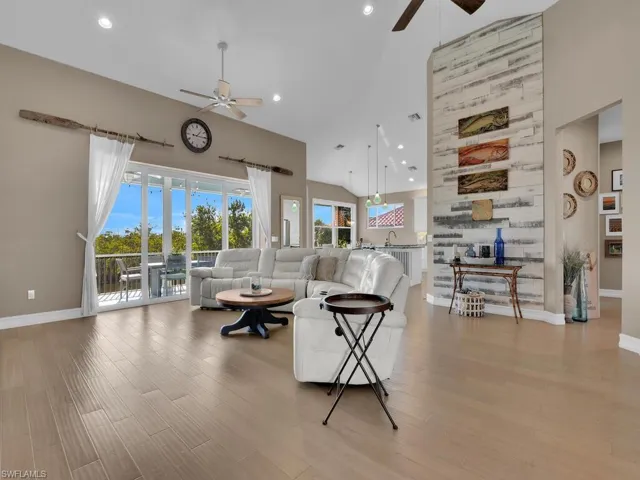 Living room featuring ceiling fan, high vaulted ceiling, and light hardwood / wood-style floors