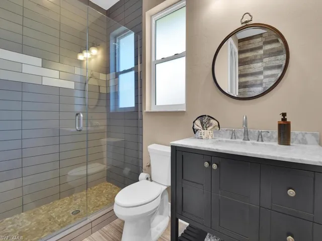 Bathroom with an enclosed shower, vanity, toilet, and hardwood / wood-style flooring