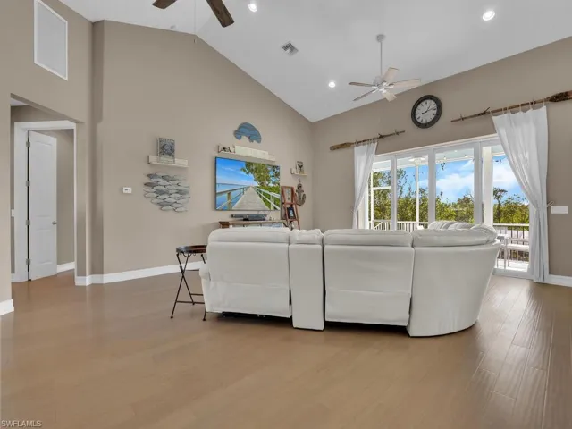 Living room featuring ceiling fan, high vaulted ceiling, and light hardwood / wood-style floors