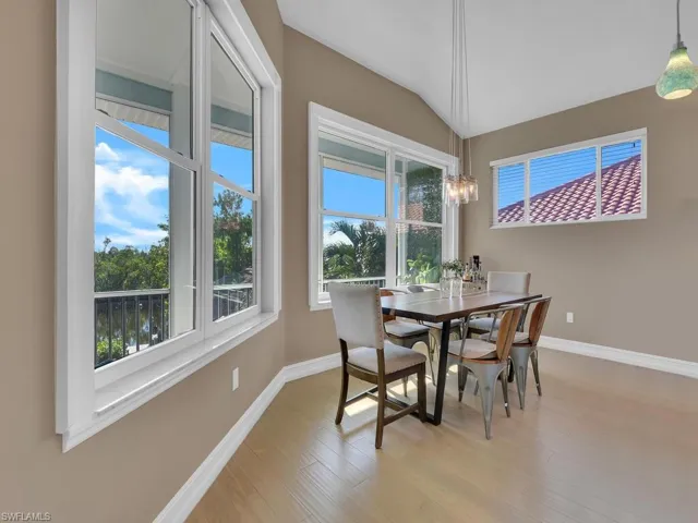 Dining room featuring a healthy amount of sunlight, light wood-type flooring, and vaulted ceiling