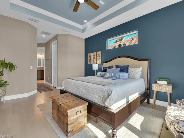 Bedroom with a raised ceiling, ceiling fan, crown molding, and light wood-type flooring