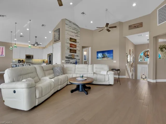 Living room with ceiling fan, light hardwood / wood-style flooring, and high vaulted ceiling