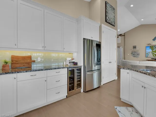 Kitchen featuring white cabinets, stainless steel fridge, tasteful backsplash, light hardwood / wood-style floors, and beverage cooler