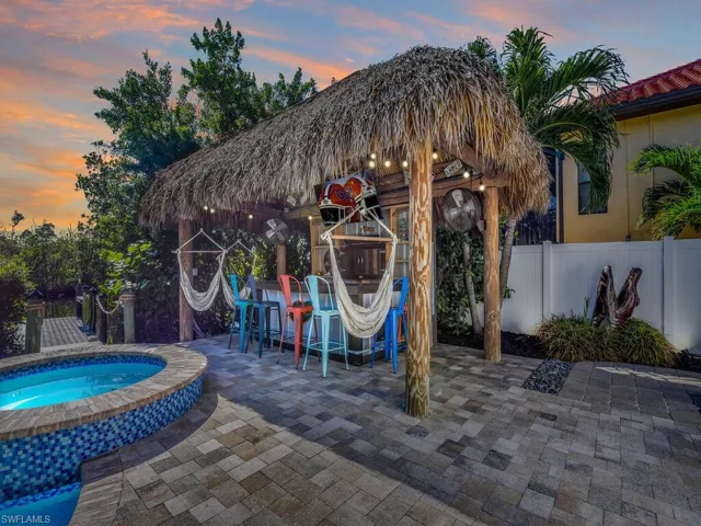 Pool at dusk with a patio area, an in ground hot tub, and exterior bar