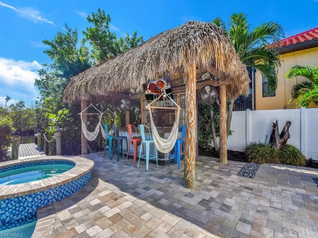 View of patio / terrace with an in ground hot tub, tiki hut & bar
