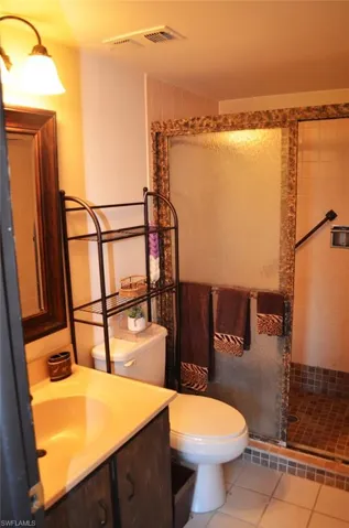 Full bath featuring toilet, a stall shower, vanity, and tile patterned floors