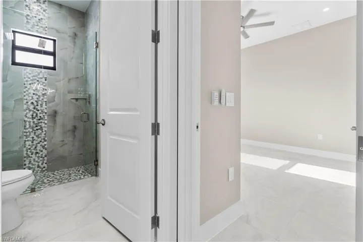 Bathroom with a marble finish shower and a ceiling fan