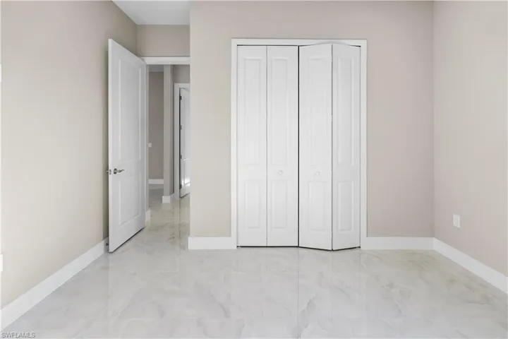 Unfurnished bedroom with light marble finish floors and a closet