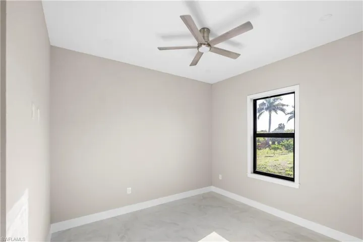 Spare room with light marble finish floors and a ceiling fan