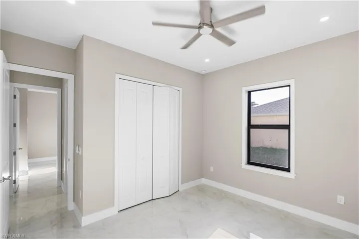 Unfurnished bedroom featuring light marble finish flooring, a ceiling fan, recessed lighting, and a closet