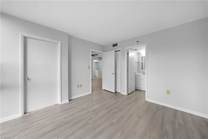 Unfurnished bedroom featuring ensuite bathroom and light hardwood / wood-style flooring