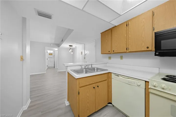 Kitchen with sink, kitchen peninsula, light hardwood / wood-style flooring, and white appliances
