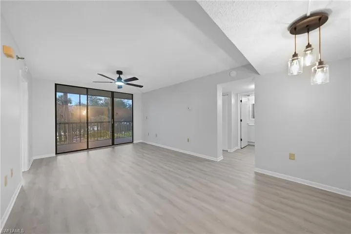 Unfurnished room featuring light wood-type flooring, expansive windows, ceiling fan, and a textured ceiling