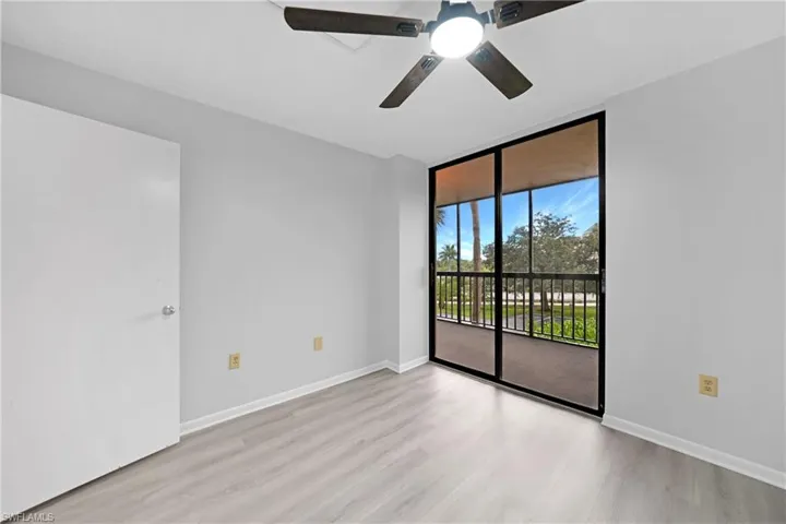 Empty room with ceiling fan, light hardwood / wood-style flooring, and floor to ceiling windows