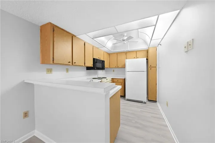 Kitchen featuring ceiling fan, light hardwood / wood-style flooring, white refrigerator, kitchen peninsula, and stove