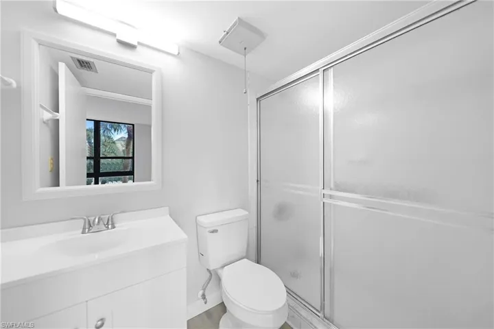Bathroom with an enclosed shower, vanity, and toilet
