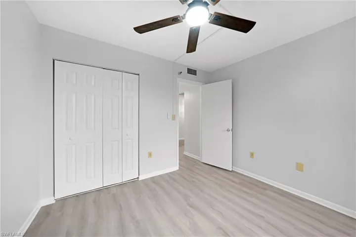 Unfurnished bedroom with light wood-type flooring, ceiling fan, and a closet