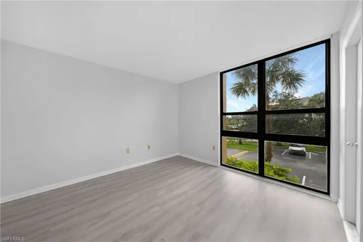 Unfurnished room with wood-type flooring and a wall of windows