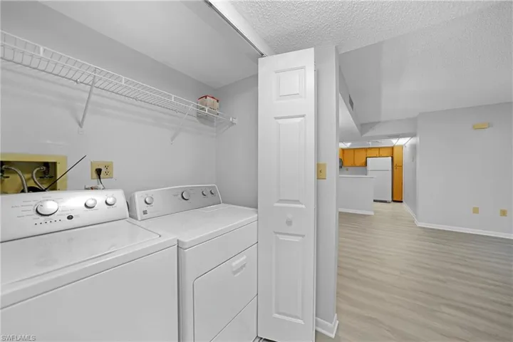 Washroom with a textured ceiling, light hardwood / wood-style floors, and washer and dryer