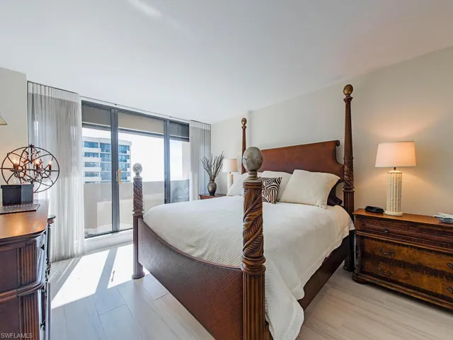 Bedroom with access to exterior, a wall of windows, and wood finished floors