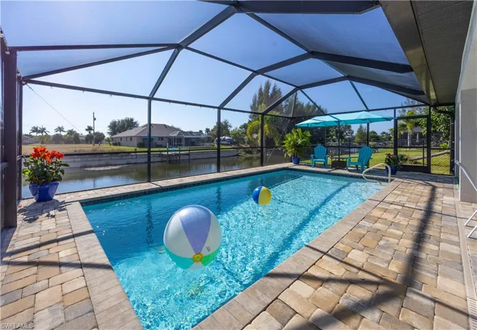 Swimming pool with a water view, a sunroom, a patio, and a lanai