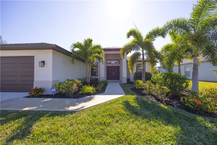 View of front of house with a front yard, a garage, and stucco siding