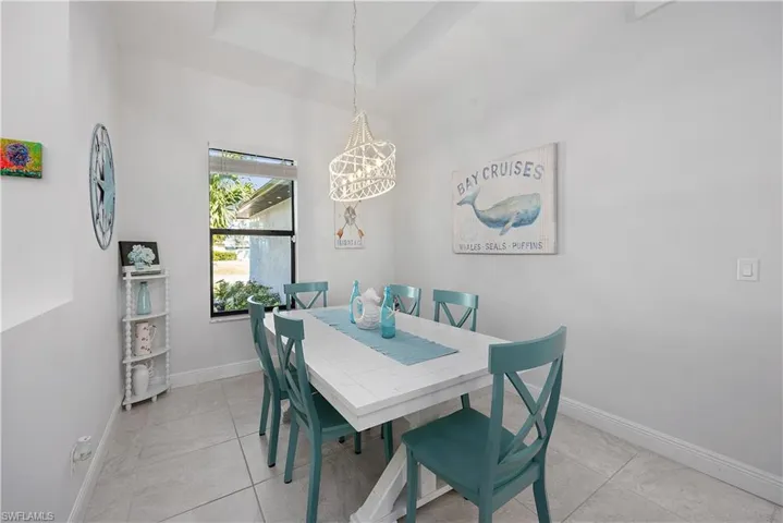 Dining area with a chandelier, a tray ceiling, and light tile patterned flooring