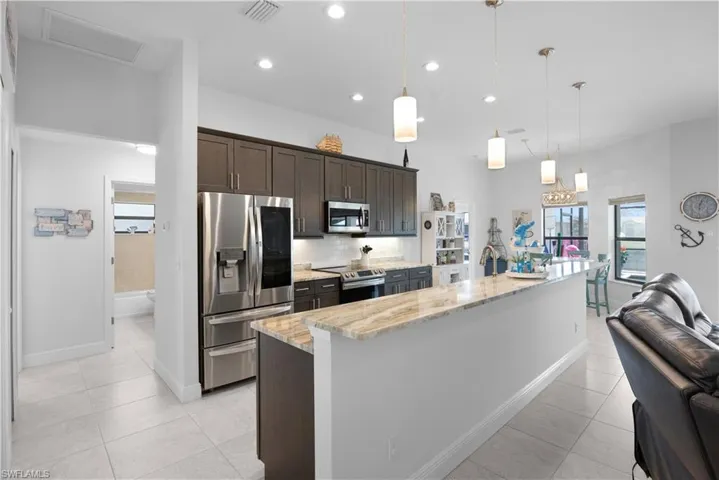 Kitchen with a large island, appliances with stainless steel finishes, dark brown cabinetry, pendant lighting, and recessed lighting