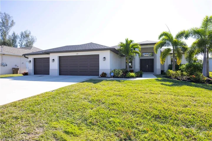 View of front of property featuring stucco siding, a front yard, concrete driveway, and an attached garage