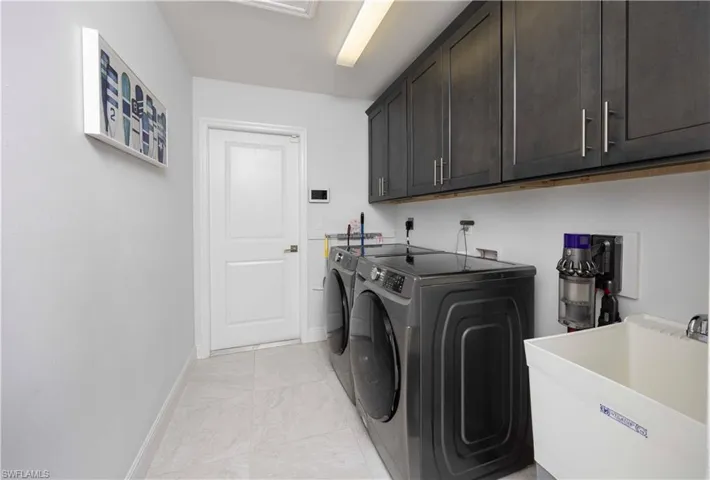 Washroom featuring washing machine and dryer, cabinet space, and light tile patterned flooring