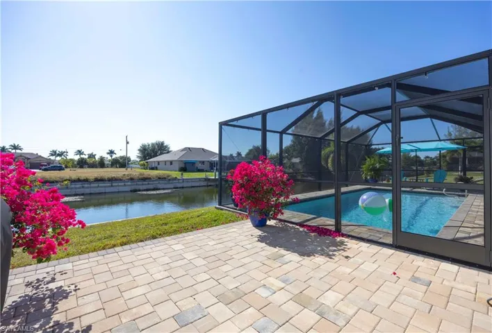Outdoor pool with a lanai, a sunroom, a patio, and a water view