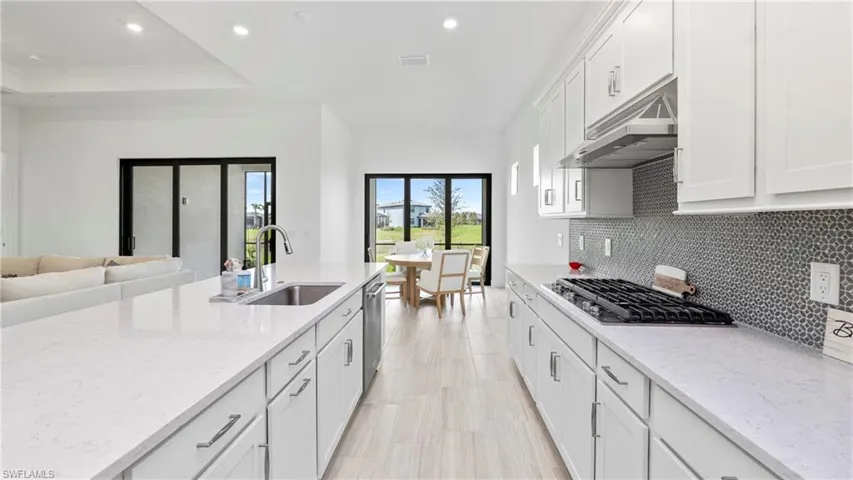 Kitchen featuring white cabinets, recessed lighting, light stone counters, stainless steel appliances, and open floor plan