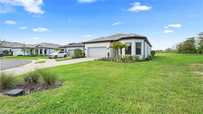 View of front facade featuring driveway, a garage, stucco siding, and a front yard