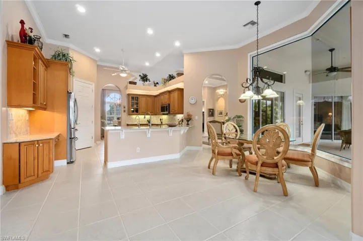 Dining area with arched walkways, visible vents, crown molding, and a ceiling fan