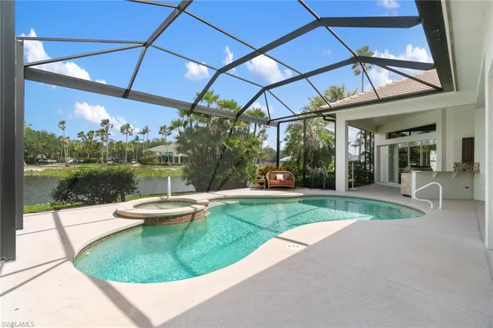 View of swimming pool featuring glass enclosure, a pool with connected hot tub, a water view, and a patio