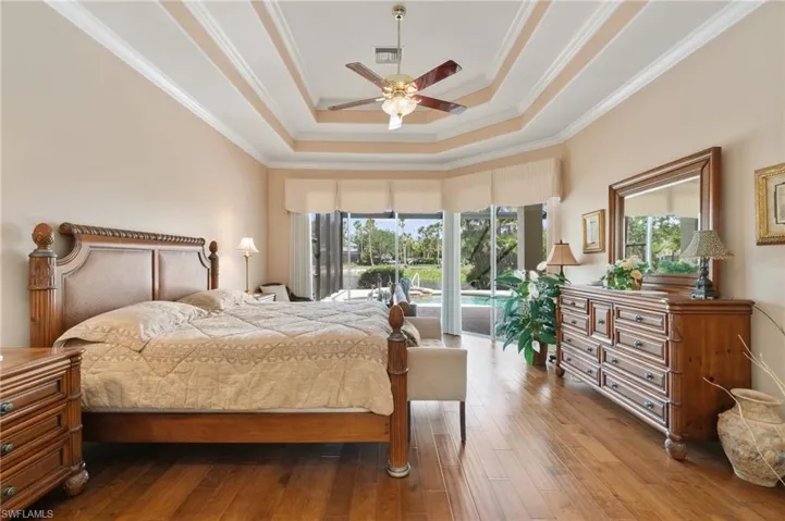 Bedroom featuring visible vents, crown molding, wood finished floors, access to exterior, and a tray ceiling
