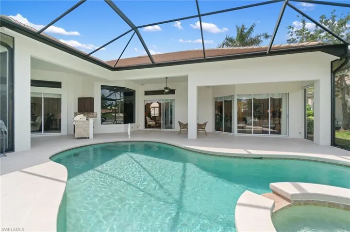 View of swimming pool featuring a patio, ceiling fan, a pool with connected hot tub, and a lanai