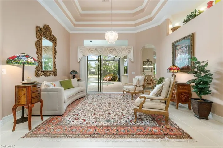 Sitting room with a tray ceiling, crown molding, tile patterned flooring, and an inviting chandelier