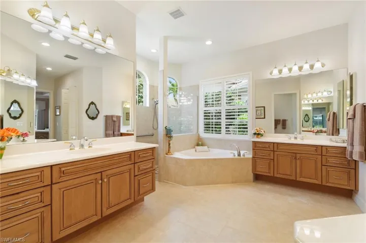 Full bathroom with a sink, two vanities, a garden tub, and visible vents