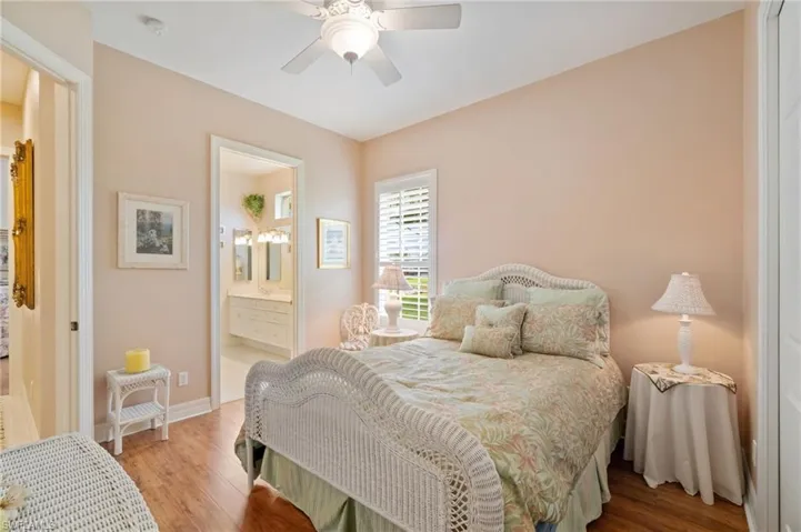 Bedroom featuring baseboards, wood finished floors, ensuite bath, and a ceiling fan