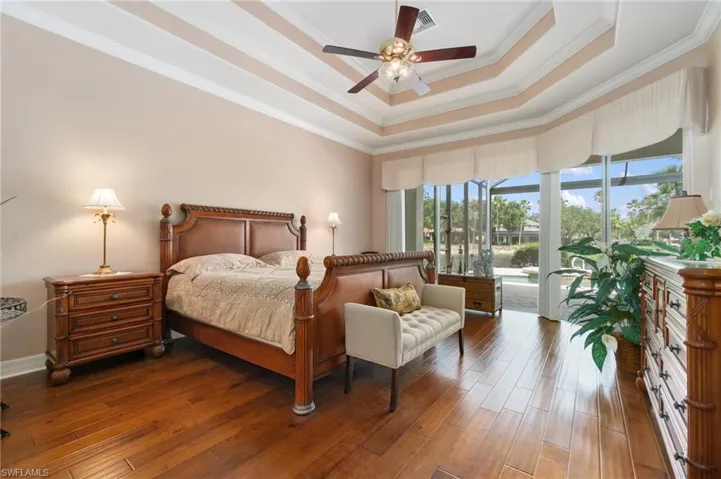 Bedroom featuring a raised ceiling, visible vents, access to outside, and wood finished floors