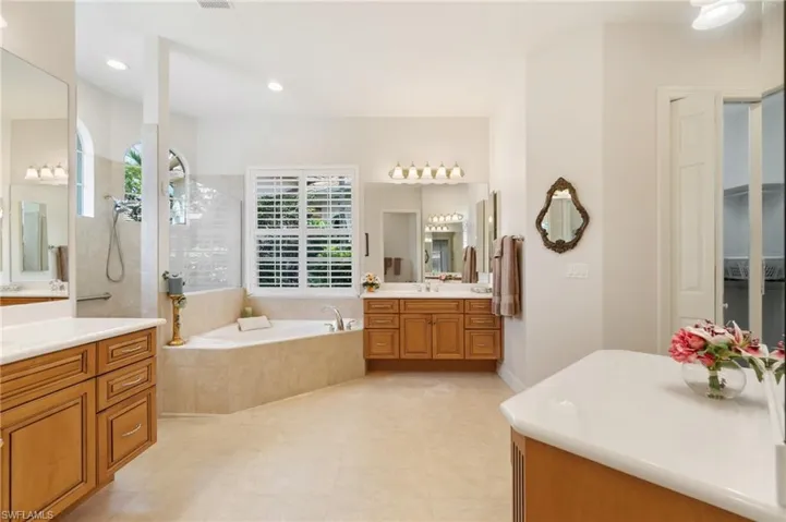 Bathroom with a walk in shower, a sink, two vanities, a bath, and recessed lighting