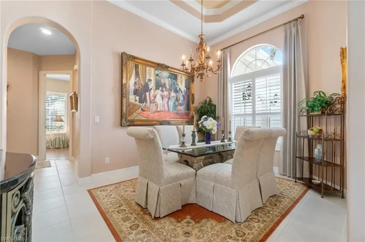 Dining space featuring crown molding, light tile patterned floors, baseboards, arched walkways, and a notable chandelier
