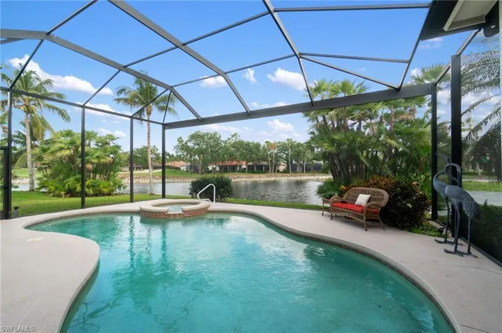 View of swimming pool featuring a pool with connected hot tub, a lanai, a water view, and a patio