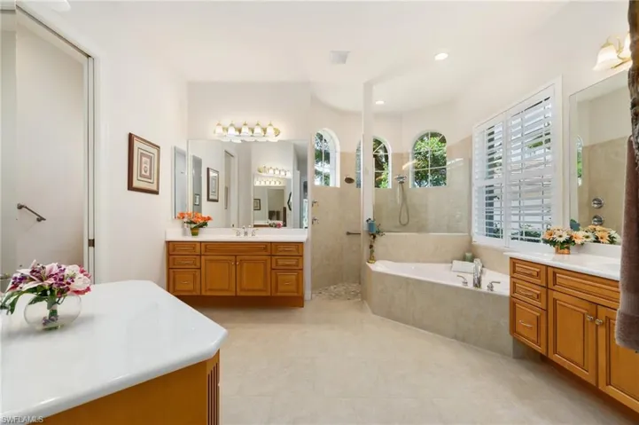 Bathroom featuring a walk in shower, a sink, two vanities, a bath, and visible vents